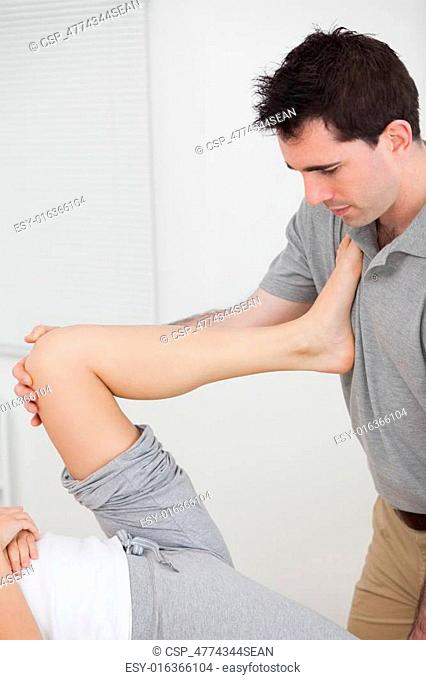 Woman putting her leg on the chest of doctor while stretching