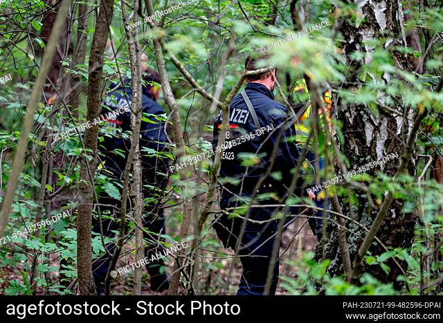 21 July 2023, Brandenburg, Kleinmachnow: Police officers run through undergrowth in the area of the southern border of Berlin