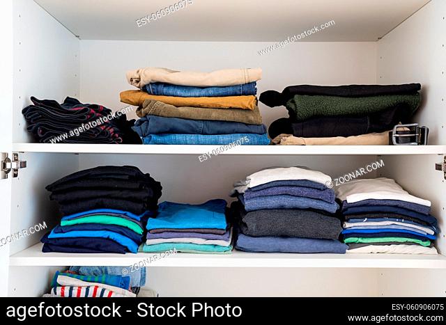 View of neatly stacked and folded colorful men's clothes in a closet