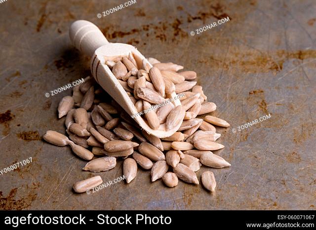 hulled sunflower seeds on steel plate and wooden scooop