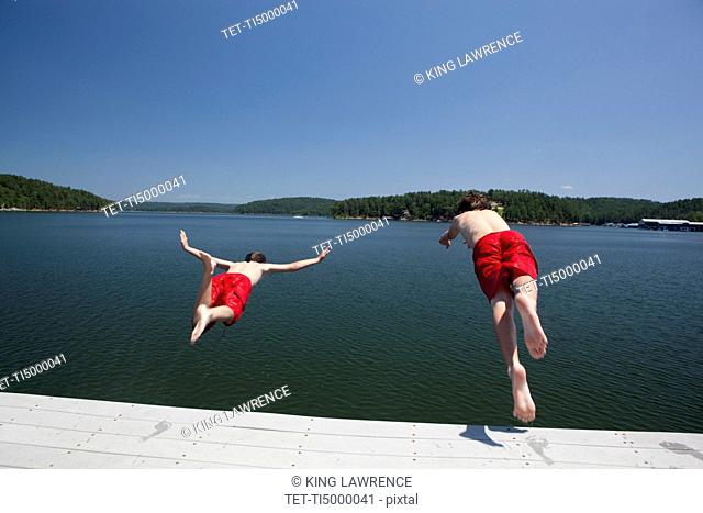 USA, Arkansas, Murfreesboro, Two brothers 8-9, 12-13 jumping into water