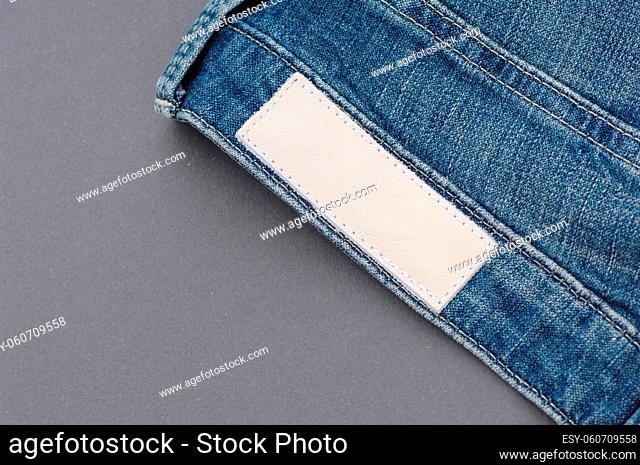 part of denim pants with back pockets and label, close-up