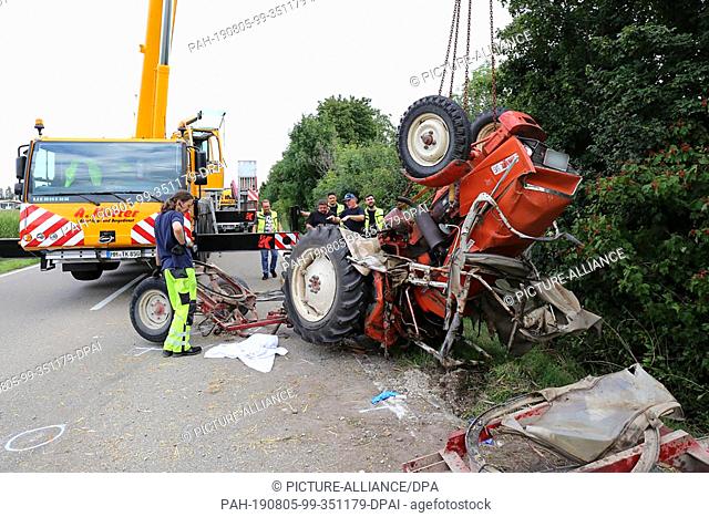 05 August 2019, Bavaria, Derndorf: The wreck of a tractor is towed away from the scene of the accident. A tractor driver died in an accident near the Swabian...