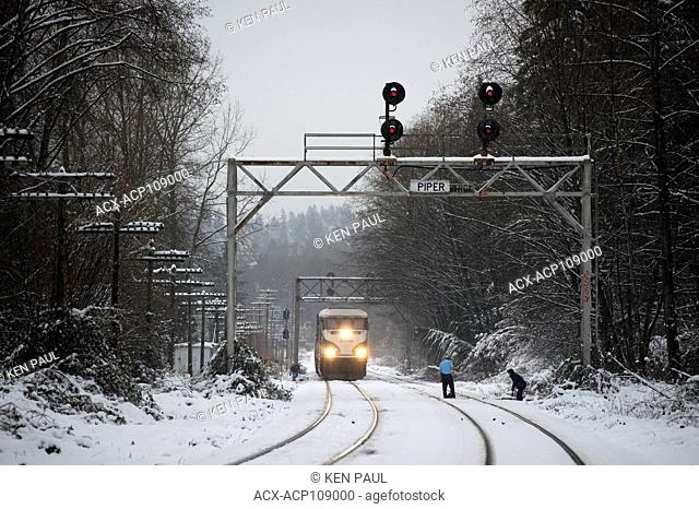 Workers clear snow from a track switch as an Amtrak Cascades train waits, Burnaby, British Columbia, Canada