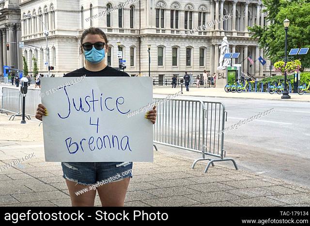 Peaceful protester holds signage demand of ""Justice 4 Breonna"" in front of armed and masked protesters at the area of Friday night’s rioting on May 30