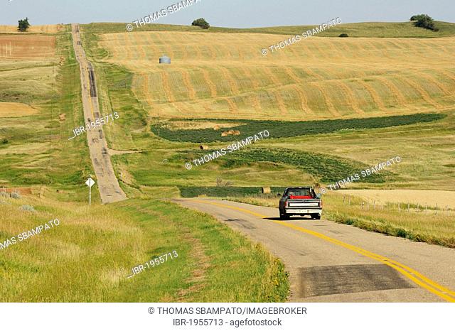 Car on a lonely road through the fields and prairies of Saskatchewan, Canada