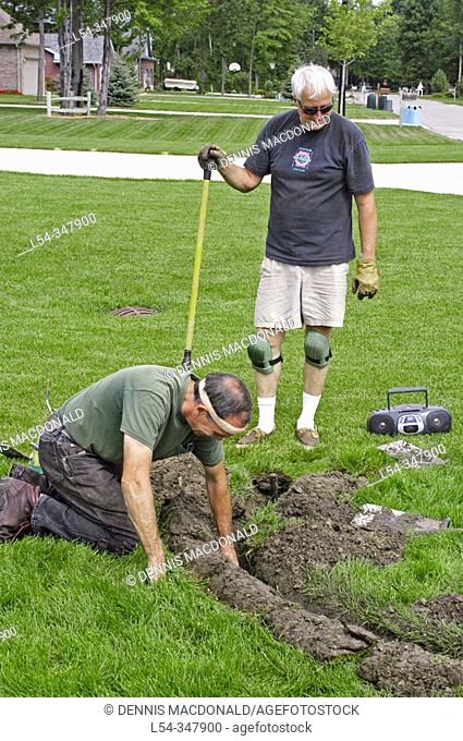 Two retired adult men working in second career install lawn irrigation systems