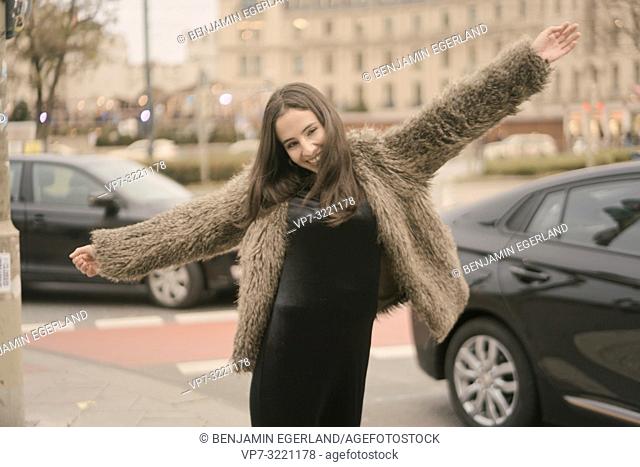 playful happy carefree woman dancing on street in city, next to car traffic, in Munich, Germany