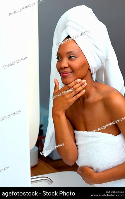 African american young woman wrapped in white towels feeling happy for her skin, copy space
