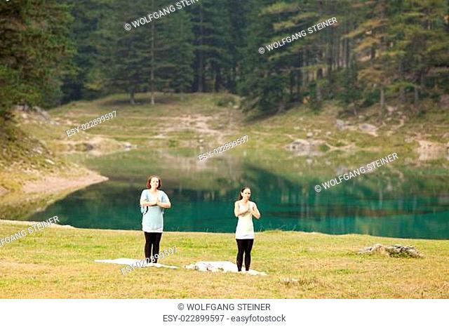 Zwei Frauen beim Yogatraining vor einem See