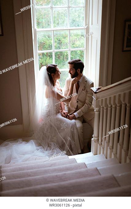 Romantic bride and groom sitting on the window sill