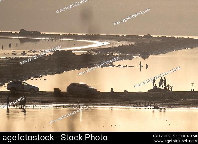 21 October 2023, Ukraine, Odessa: People sitting in the evening light on land near mouth of the river Velykyj Kujalnyk into the Black Sea