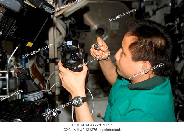 Astronaut Edward T. Lu, Expedition 7 NASA ISS science officer and flight engineer, cleans the dust off the charged couple device (CCD) on a digital still camera...
