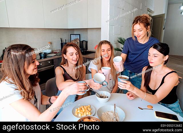 group of women in the kitchengroup of girls sitting at the table in the kitchen and having lunch