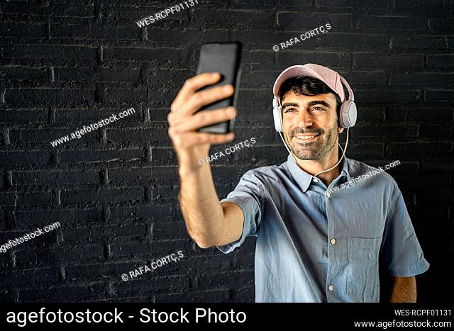 Smiling man taking selfie through smart phone