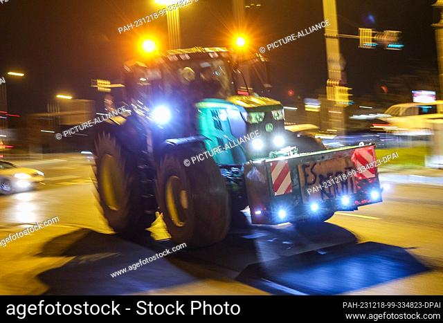 dpatop - 18 December 2023, Saxony, Leipzig: One of several farmers drives through the early morning rush hour traffic with his tractor and a protest poster