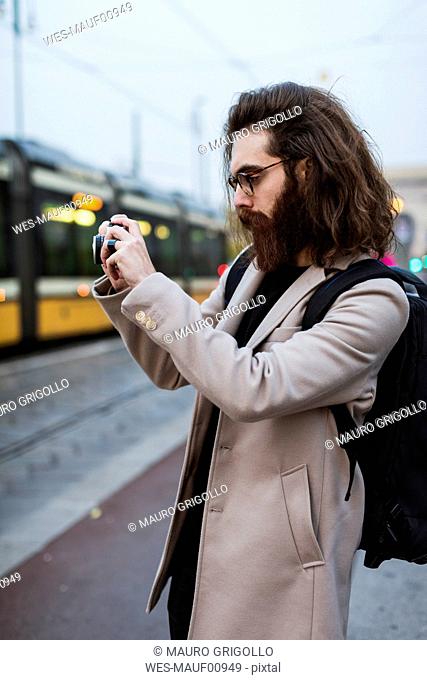 Stylish young man outdoors taking pictures in the city