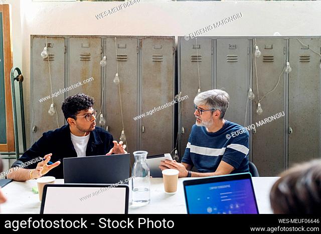 Businessmen discussing at desk in coworking office