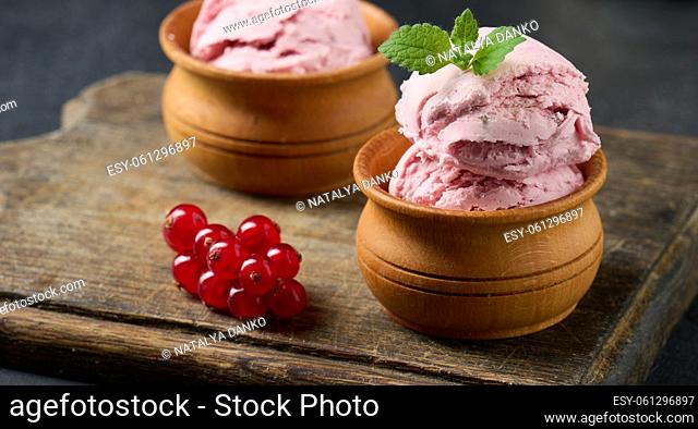 Pink scoops of popsicles with red currants on a black table. Ice cream