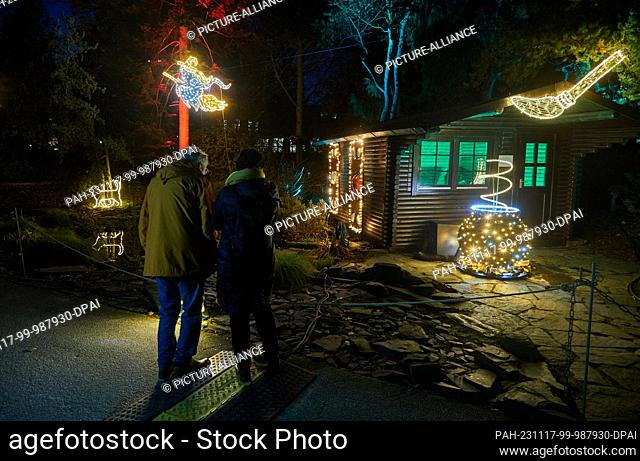 17 November 2023, Hamburg: The first visitors stand in front of a colorfully decorated witch's cottage in the ""Christmas Garden"" in the Loki Schmidt Garden