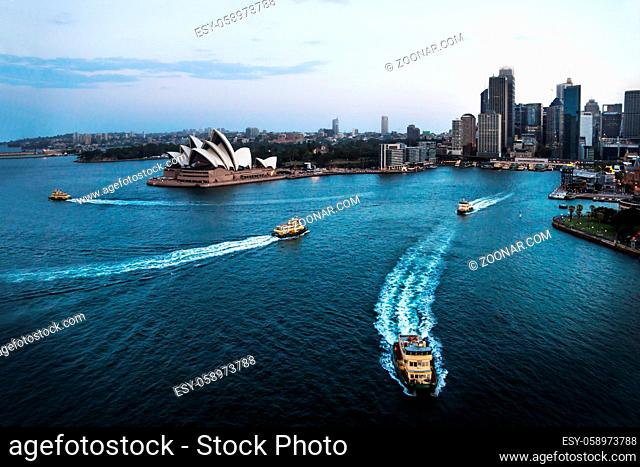 Cityscape of Sydney with Opera house, ferry boats in the ocean and Downtown skyscrapers after sunset, Sydney, Australia