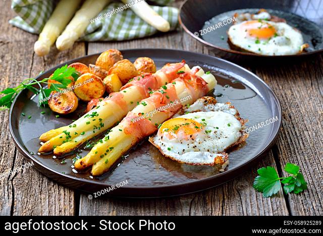 Gebackener Spargel mit Speckstreifen, Ofenkartoffeln und Spiegelei ?Baked white asparagus with bacon strips, crunchy potatoes and fried eggs