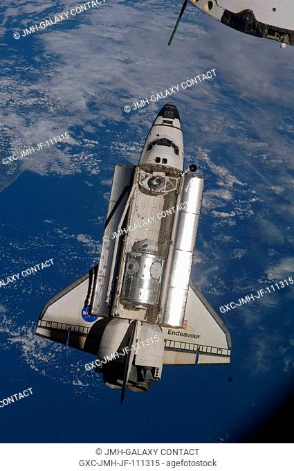 Backdropped by a blue and white part of Earth, space shuttle Endeavour is featured in this image photographed by an Expedition 22 crew member as the shuttle...