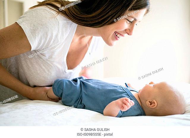 Mother playing with baby boy, face to face, smiling