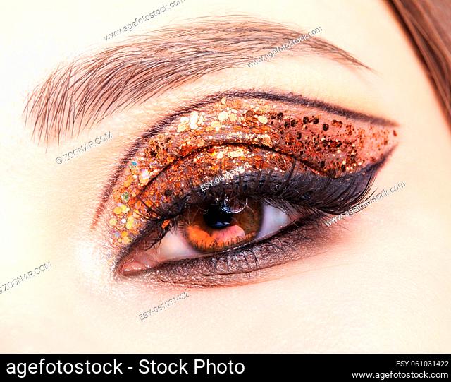Close-up shot of female face with vogue golden shining eyes makeup