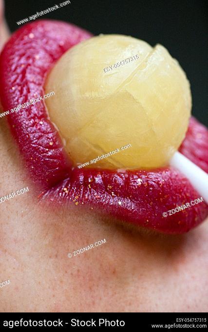 Close up view of some red lips with a lollipop