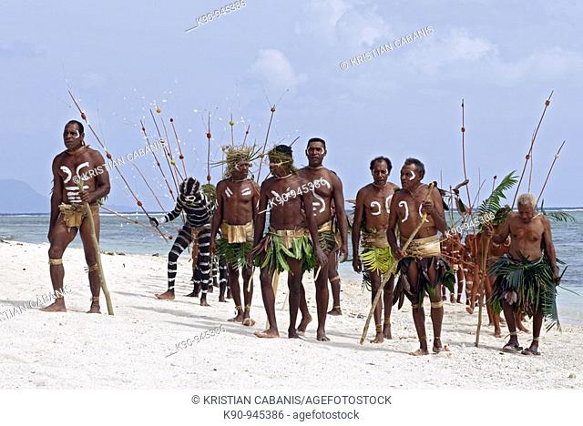 Melanesian men in traditional Snake Dance body paint, headdress and weapons at the beach of Ra Island with the Pacific Ocean in the background, Banks Groups