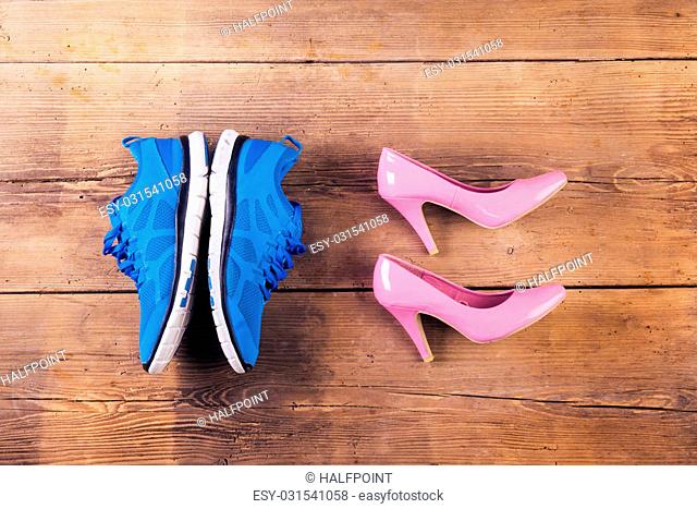 Running shoes and pink court shoes on a wooden floor background
