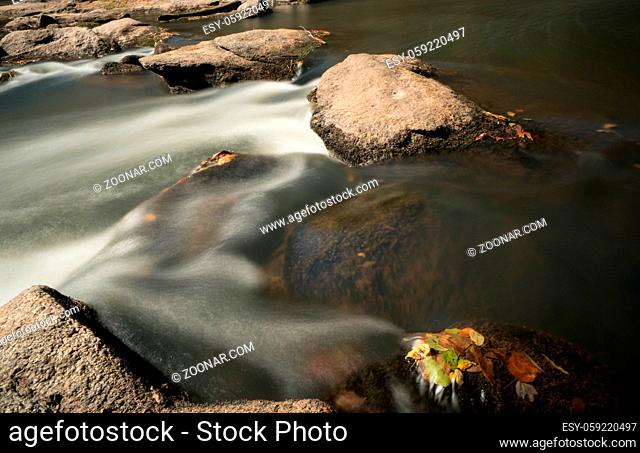idyllic mountain stream with rocks and fall foliage and a small waterfall in South Carolina in late autumn