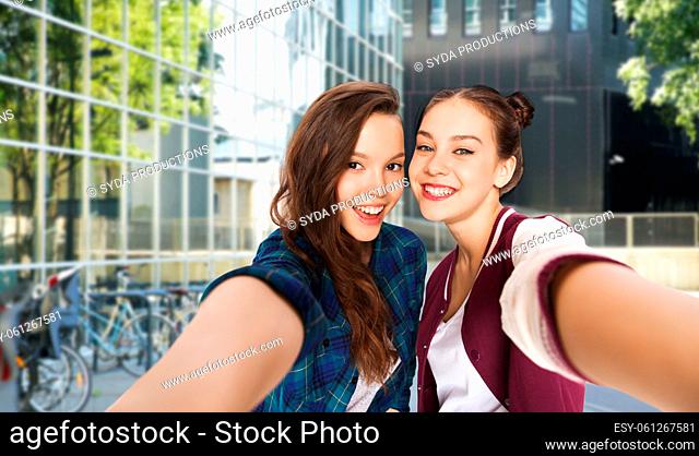 happy teenage girls taking selfie on city street