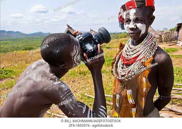 Korcho Ethiopia Africa village Lower Omo Valley Karo tribe with painted faces with boy using modern camera taking photos 25