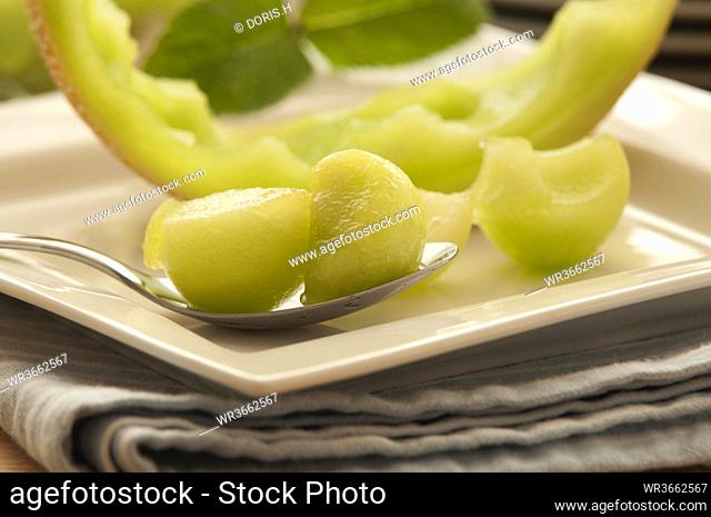 Plate of honeydew melon with spoon on napkin, close up