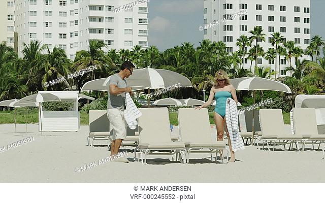 WS Couple relaxing on deckchairs on beach / South Beach, Miami, Florida, USA
