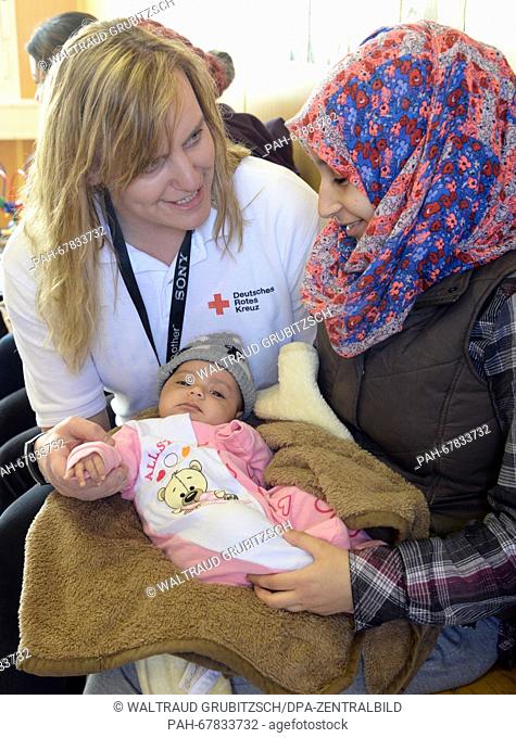 Mandy Baeumler (L), team leader of the German Red Cross (DRK), looks after Haya Diwabi from Syria and her three-month-old daughter in the Neue Messe refugee...