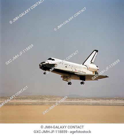 The space shuttle Columbia with its landing gear in position near touchdown on a dry lakebed at Edwards Air Force Base in the desert area of southern California