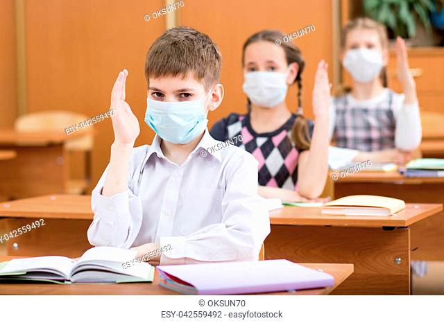 schoolkids with protection mask against flu virus at lesson in classroom