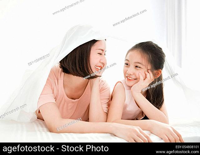 beautiful mother and child girl relaxing and playing in the bed