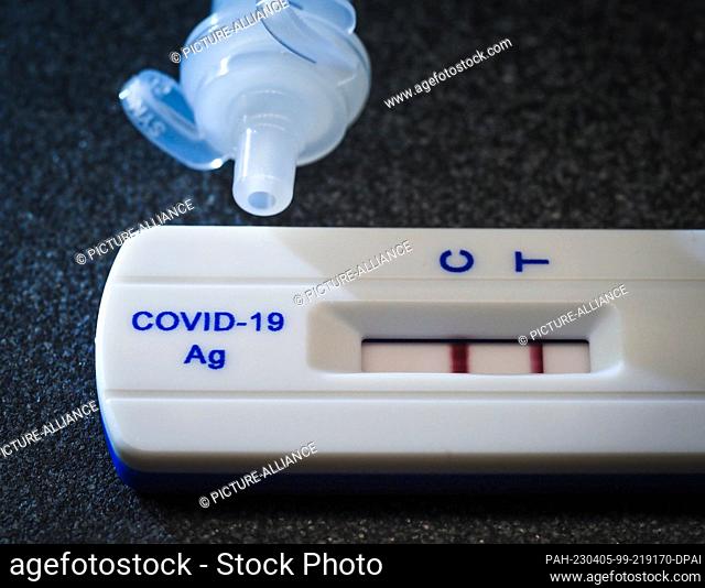 09 February 2023, Berlin: A commercially available test for Covid-19 shows two red stripes and thus a positive result. Next to it is the tube with the test...