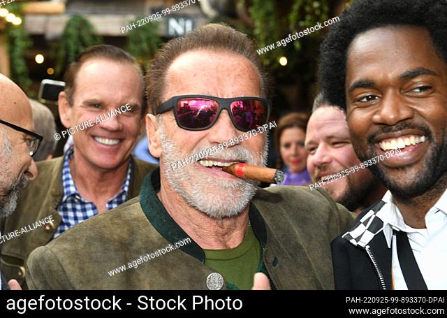 25 September 2022, Bavaria, Munich: Actor Arnold Schwarzenegger (l) shows off with actor Milan Carter( r) m Käfer Festzelt at the Munich Oktoberfest