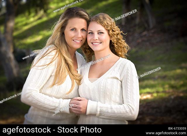 Pretty mother and daughter portrait hugging in the park on a fall day