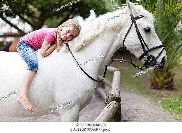 Smiling girl riding horse in yard