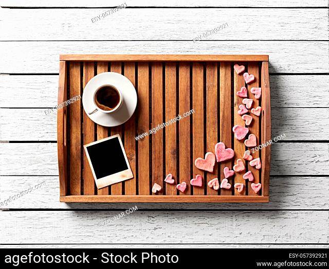 Instant photo frame and many cute hearts with cup of coffee on wood