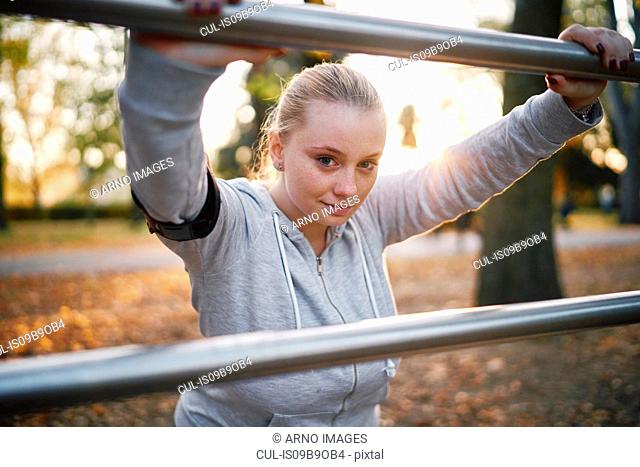 Curvaceous young woman training, portrait leaning against handrail in park