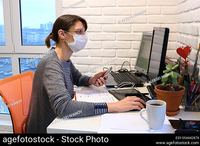 A sick girl in a medical mask in self-isolation works remotely