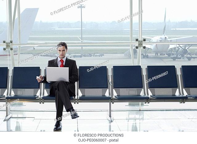 Businessman in airport with laptop and mobile phone. Barcelona El Prat Airport. Spain