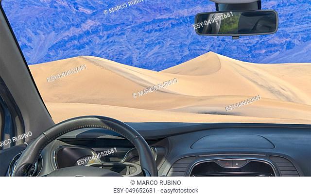 Looking through a car windshield with view of sand dunes, in the desertic zone of Death Valley, California, USA